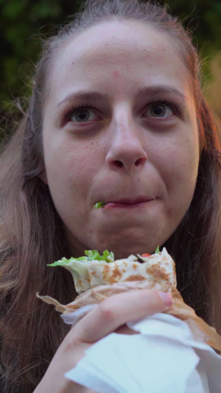 A female foodie tries a freshly made vegan falafel duner from a small street cart during her walk through Sofia