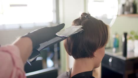 Manos-De-Un-Peluquero-Caucásico-Destacando-El-Cabello-De-Una-Clienta-En-El-Salón,-En-Cámara-Lenta