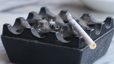 a cigarette lying in a black ashtray