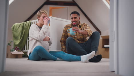 pareja esperando un bebé con bebidas calientes en la guardería de la nueva casa junto con la mudanza en cajas