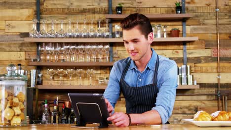 camarero masculino usando una tableta digital en el mostrador
