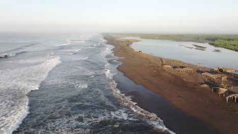 Flying-low-above-black-sand-beach-at-El-paredon-Guatemala-during-sunrise---Drone-shot