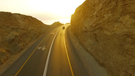 Summer-travelers-driving-with-mounted-bikes-on-the-roof-during-sunrise-in-the-Desert-cliff