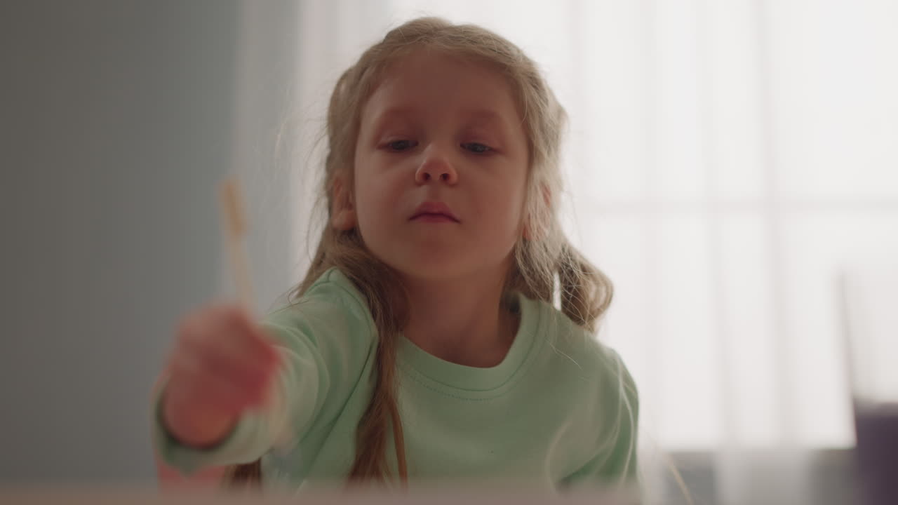 Pretty little girl draws with stick making marbling pattern