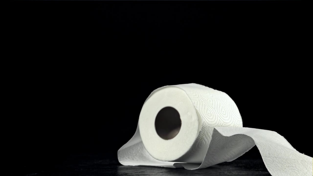 Toilet paper roll falling and unrolling on black background