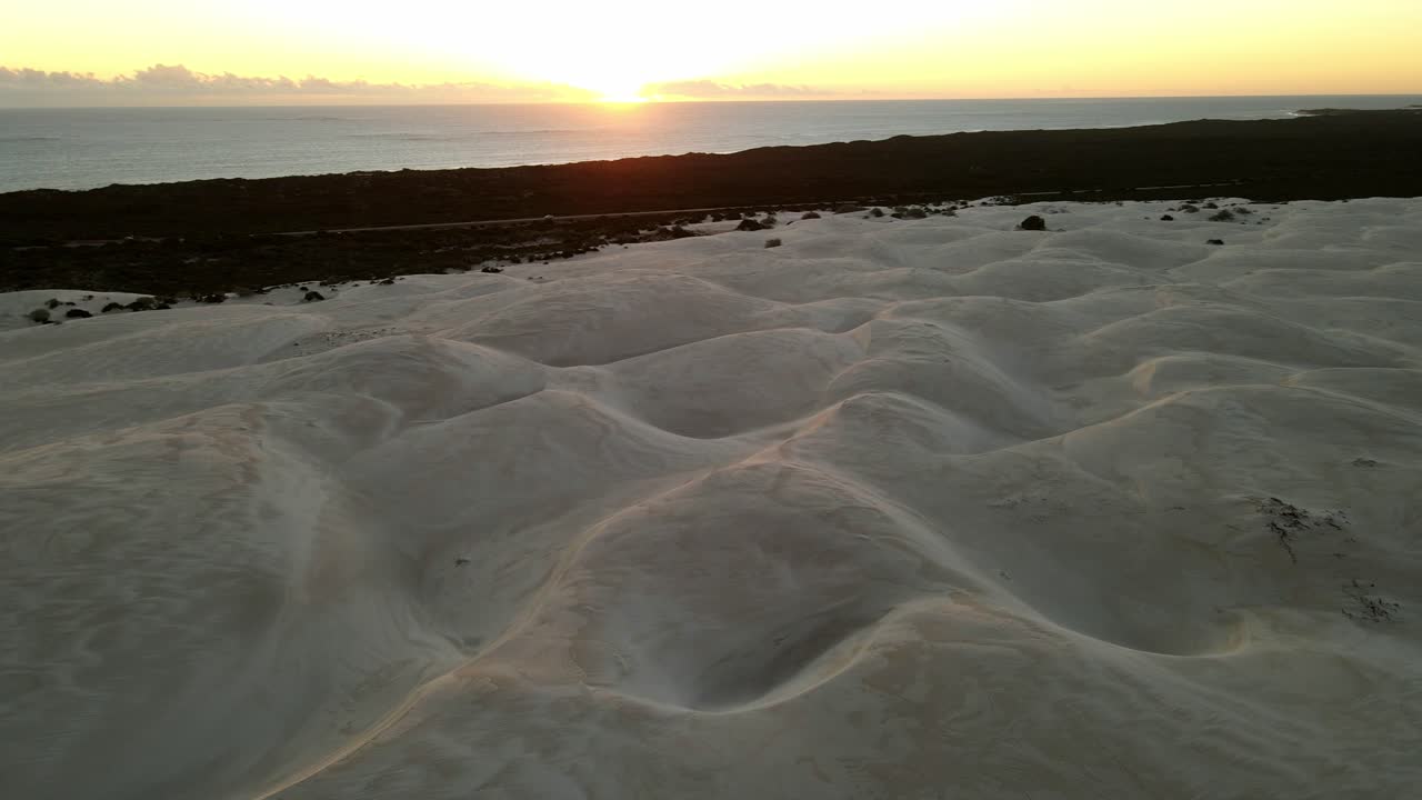 Desert circling at sunset with drone with ocean in the background