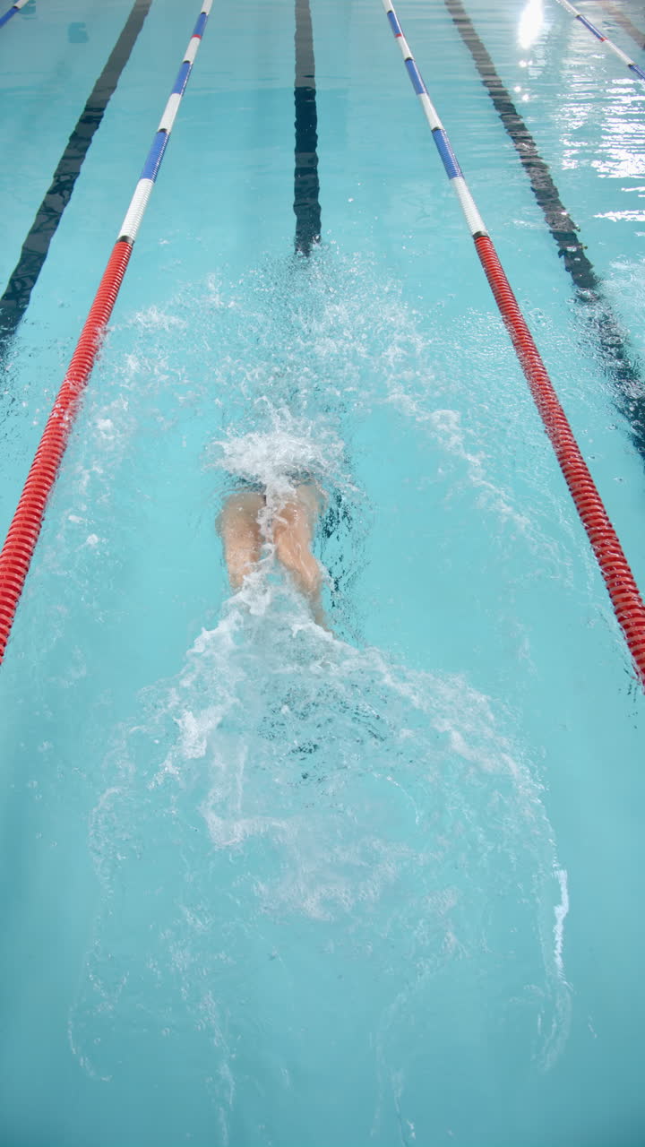 Video vertical: Atleta nadando de espalda en la piscina, entre las corcheras