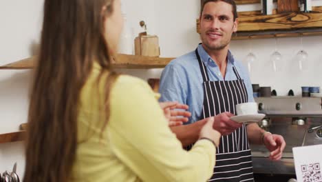 video of happy caucasian male seller in coffee shop and female customer with coffee