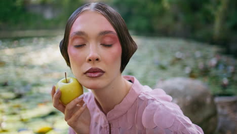 fashion model posing apple sitting at forest lake close up. woman posing nature