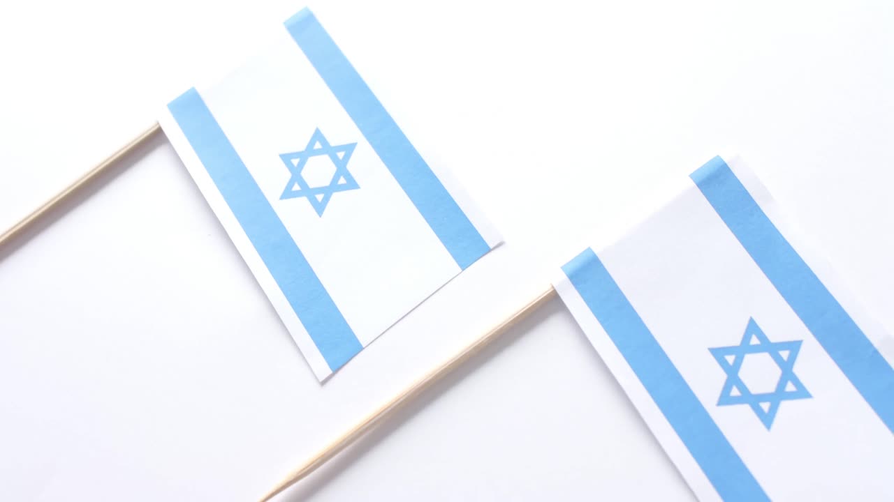 Primo piano di tre bandiere di Israele adagiate su sfondo bianco.