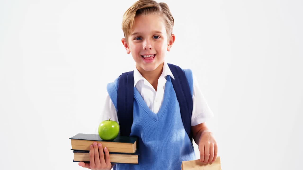 Lächelnder Schuljunge hält Bücher und Mittagessen