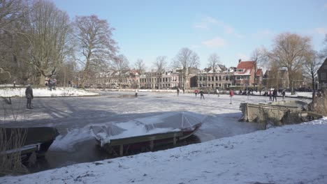 dutch locals ice skating on frozen river in old town, traditional winter scene