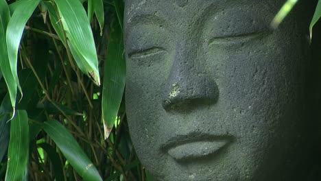 close-up of statue of jizo surrounded by bamboo