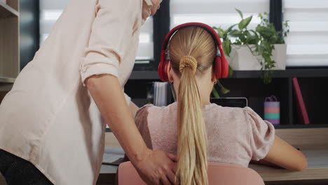 Teacher-or-parent-helping-a-girl-who-is-working-with-a-laptop-in-the-classroom