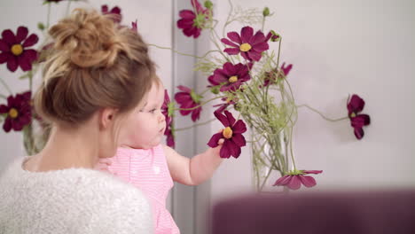 adorable baby touching flowers at home