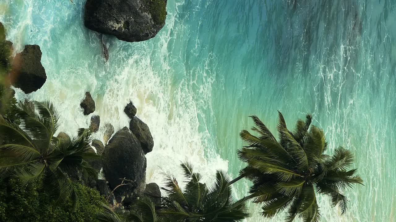 Filmagem vertical portátil das falésias de Nusa Penida em Bali, Indonésia, com vista para o mar azul com ondas na Diamond Beach e falésias em uma bela manhã