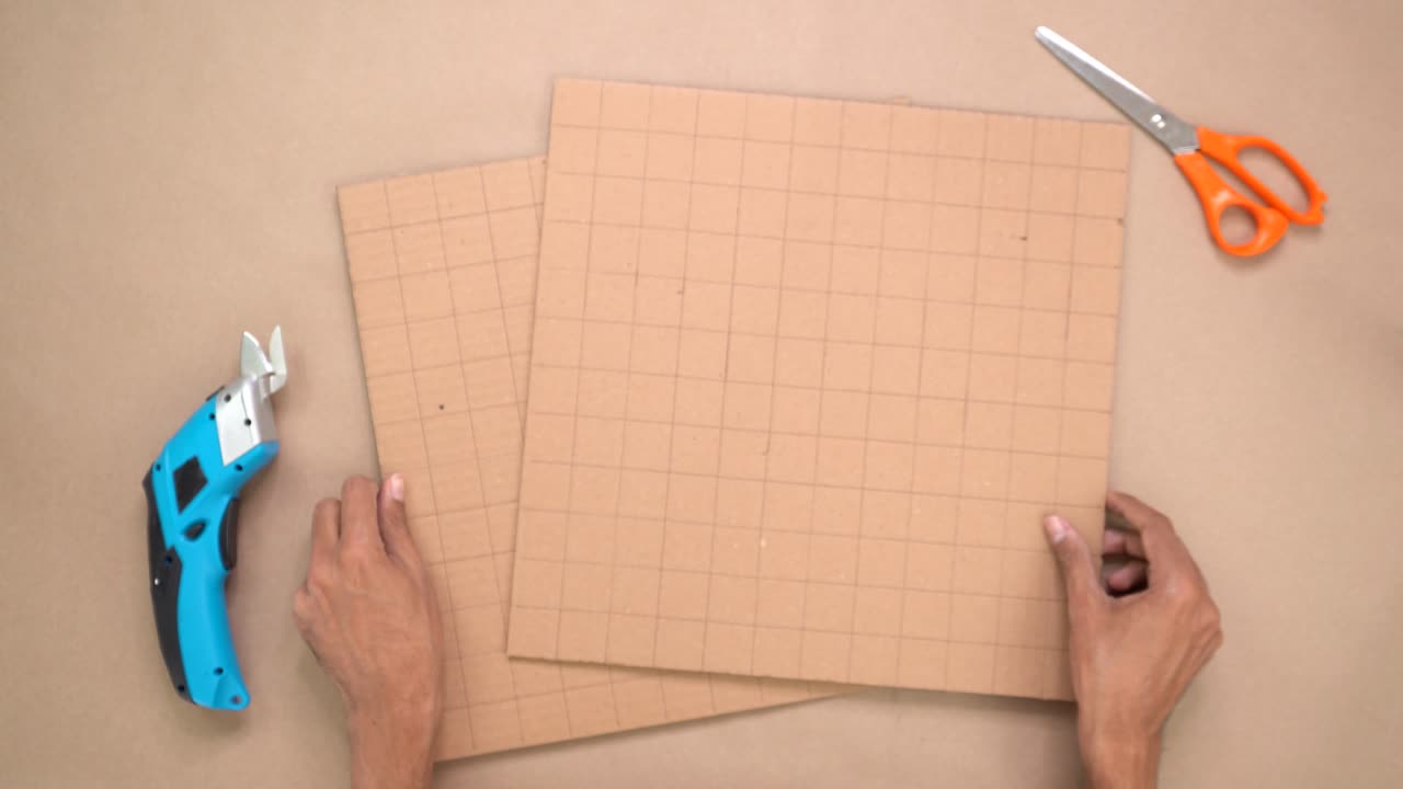 Hands rearranging cardboard with checkered pattern, arts and crafts
