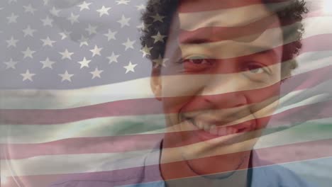 Animation-Der-Wehenden-Flagge-Amerikas-über-Einem-Lächelnden-Biracial-Mann,-Der-Vor-Dem-Meer-Steht