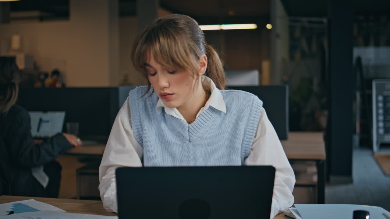 Serious girl typing laptop in office interior closeup. Woman looking computer