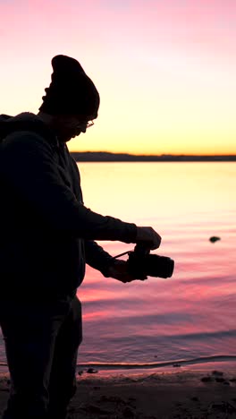 photographer silhouette capturing a colorful sunset by the water