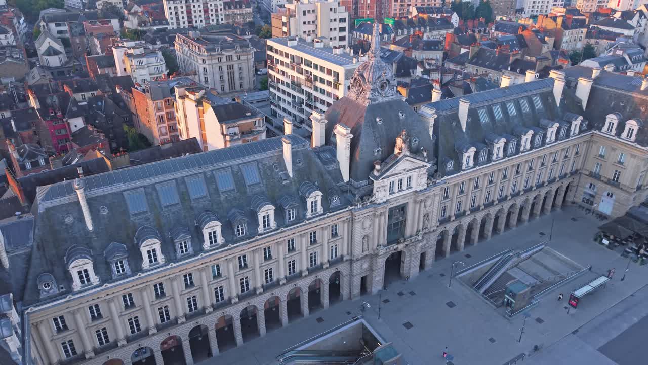 Drone advancing in top-down view over Palais du Commerce in Rennes, France revealing its façade at sunrise