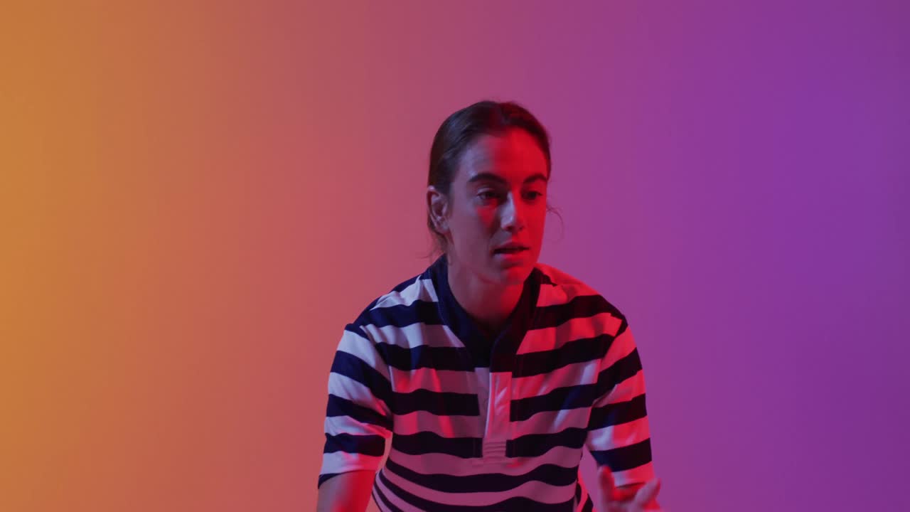 jugadora de rugby caucásica atrapando una pelota de rugby sobre la iluminación rosa de neón