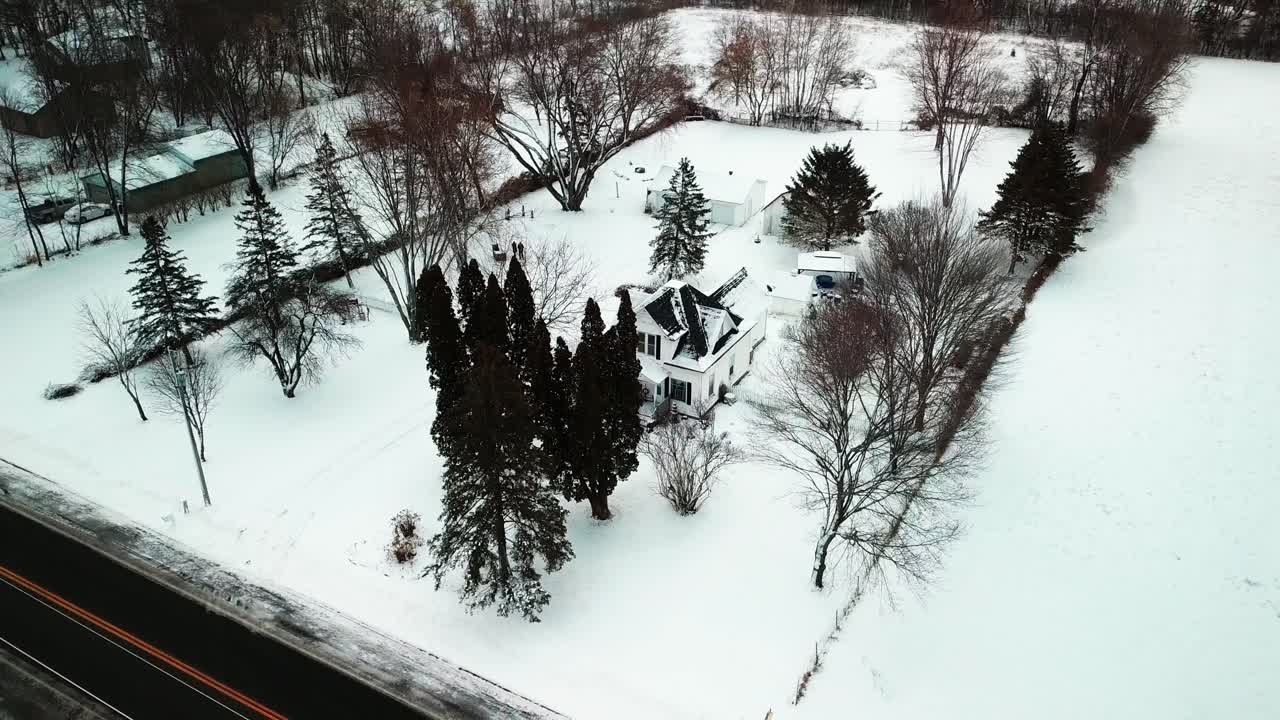 Aerial orbital shot around a 19th century farmhouse during snowy winter. 4K