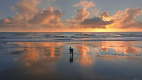 couple in silhouette during sunset at three sisters beach in new zealand