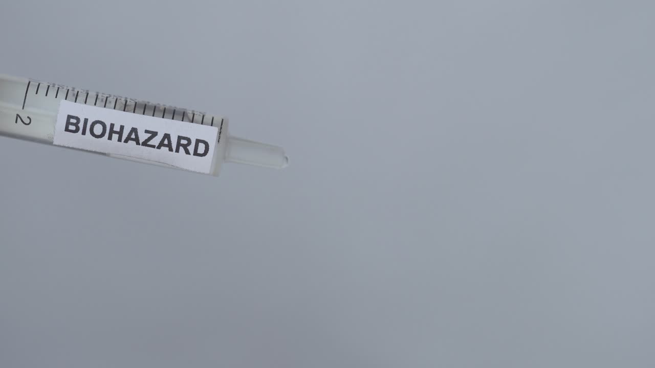 рука извлекает иглу из шприца биологической опасности - вакцина против коронавируса - крупный план