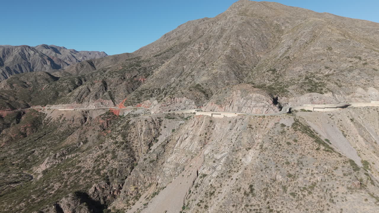 Vista aerea della sezione pavimentata di grigio della Ruta 40 RN, in netto contrasto con le formazioni geologiche rosso intenso e ocra e le montagne ricche di colore della Cuesta de Miranda a Chilecito, La Rioja, Argentina