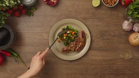 crop person putting fresh vegetable salad on plate with sausages