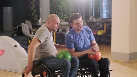 two young disabled men in wheelchairs playing bowling in the club