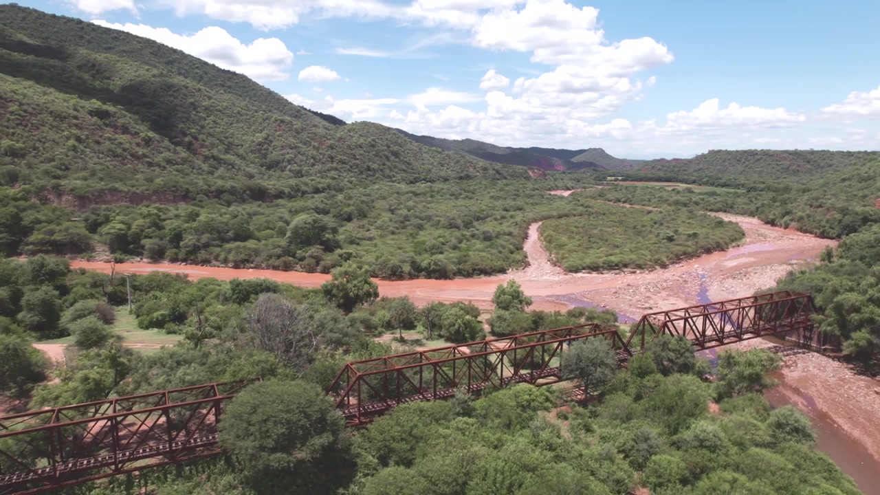 Vista aérea 4K de drone de Alemania, Salta, Argentina. Vila ferroviária histórica com uma antiga estação de trem, ponte e rio cercada por montanhas verdes exuberantes e vales cênicos do norte da Argentina