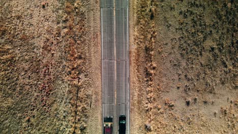 aerial top down view of a black car on a highway in the middle of the desert in the united states