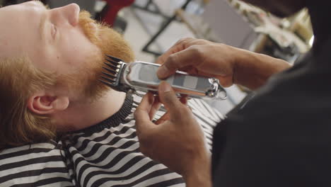 man getting his beard trimmed by barber in salon