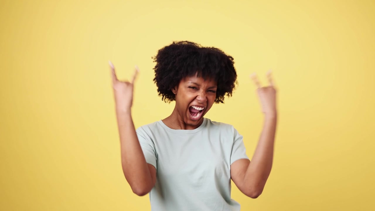 Energetic African American Woman Shouting and Making Rock and Roll Hand Gestures