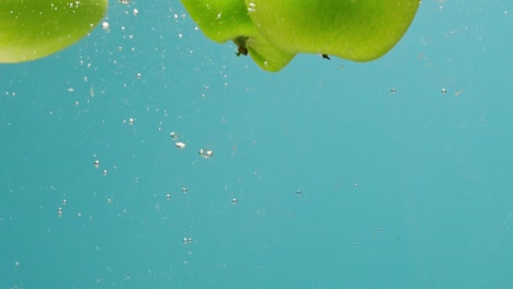 green apple slices underwater with splash