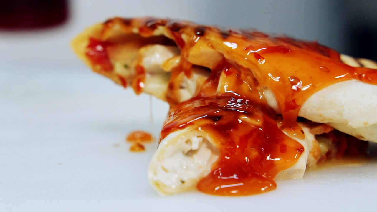 Red sauce pouring on cooked shawarma. Tasty gravy flows on mouth-watering pita. Yummy snack in the restaurant. Close-up