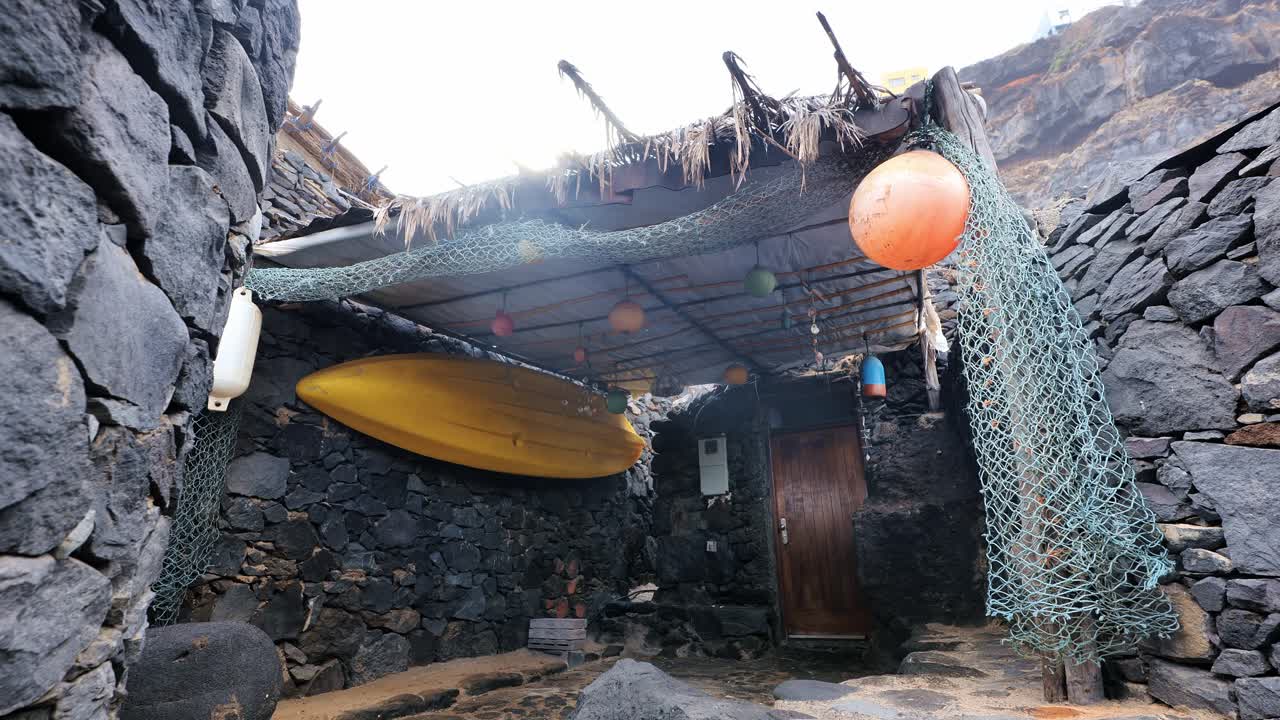 Colorful fishing hut roof with hanging kayak in volcanic stone village shelter