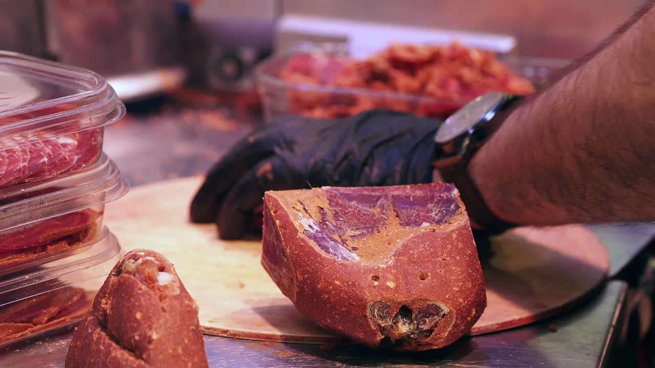 Macellaio professionista che affetta salumi su un tagliere di legno
