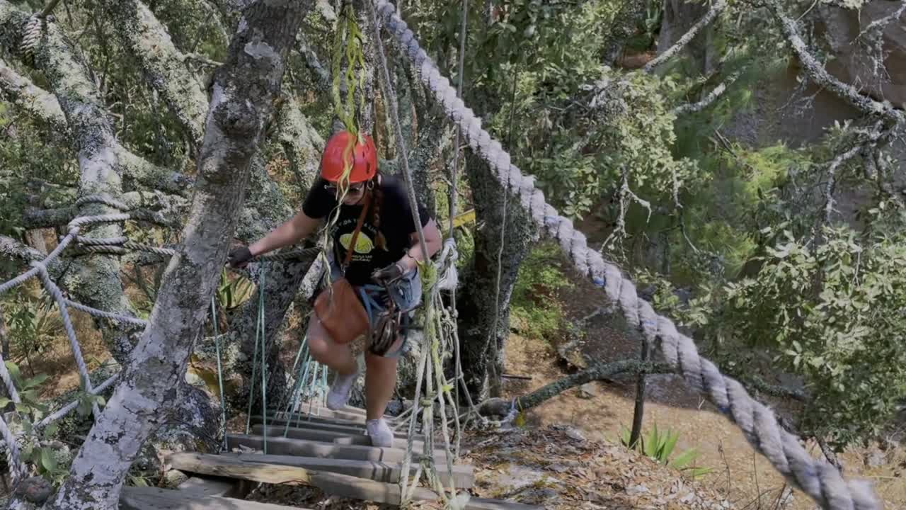 Woman climbing a suspension bridge in forest for ziplining adventure. Adventure travel in Mexico, Tapalpa. High altitude zip-line