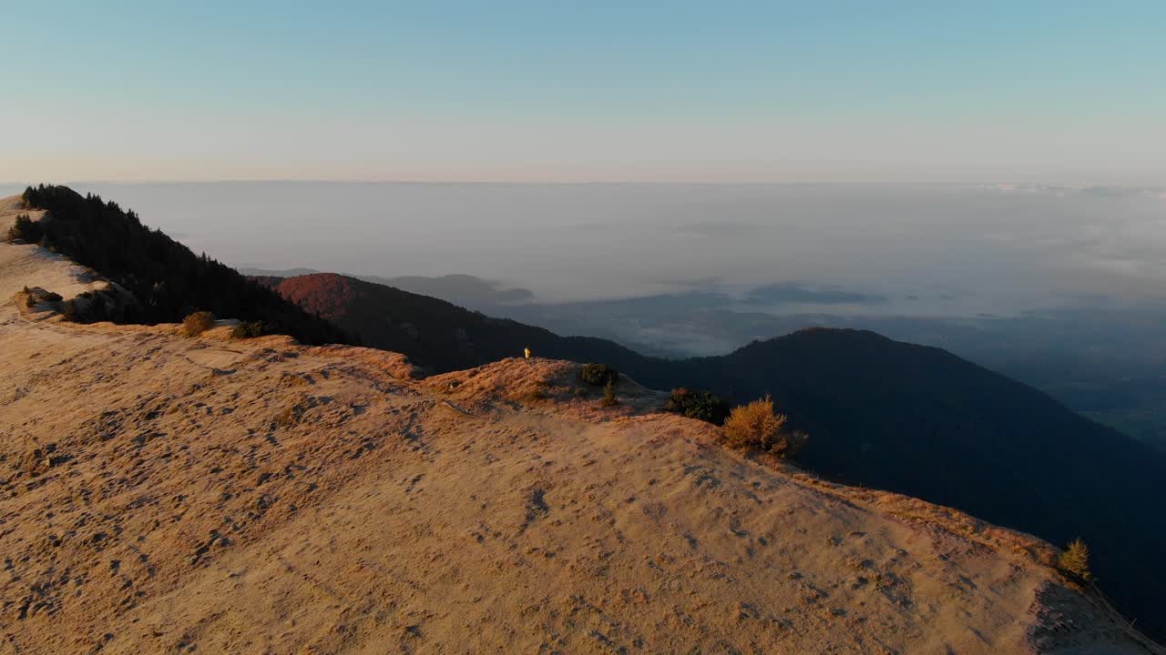 Uomo in piedi su un tranquillo altopiano montano con nebbia all'alba, Velika Planina, Slovenia