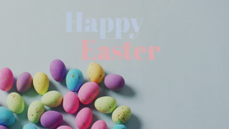 animation of happy easter text over colourful easter eggs on grey background