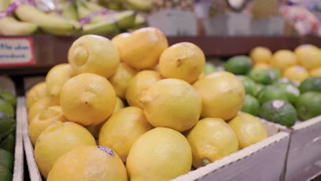 lemon crate in grocery store aisle with ripe limes and other tropical fruits