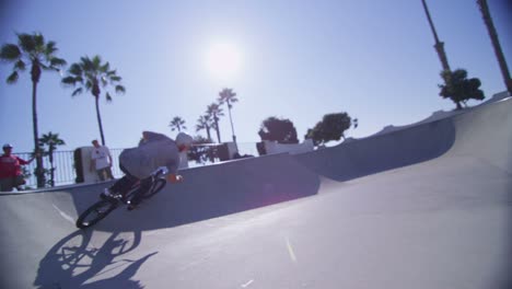 la cámara sigue a un ciclista de bmx mientras salta y monta la pared de un skatepark 1
