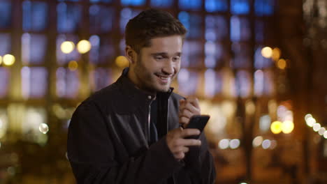 surprised man reading sms mobile phone outdoors. happy guy looking phone screen