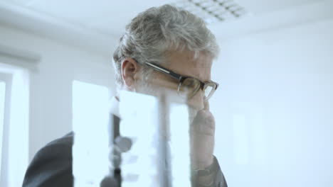 serious handsome mature ceo walking in his office and talking on phone