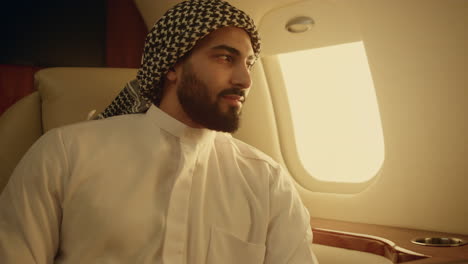 un musulman souriant pose dans un avion privé. un carnet de gadgets en gros plan sur la table.