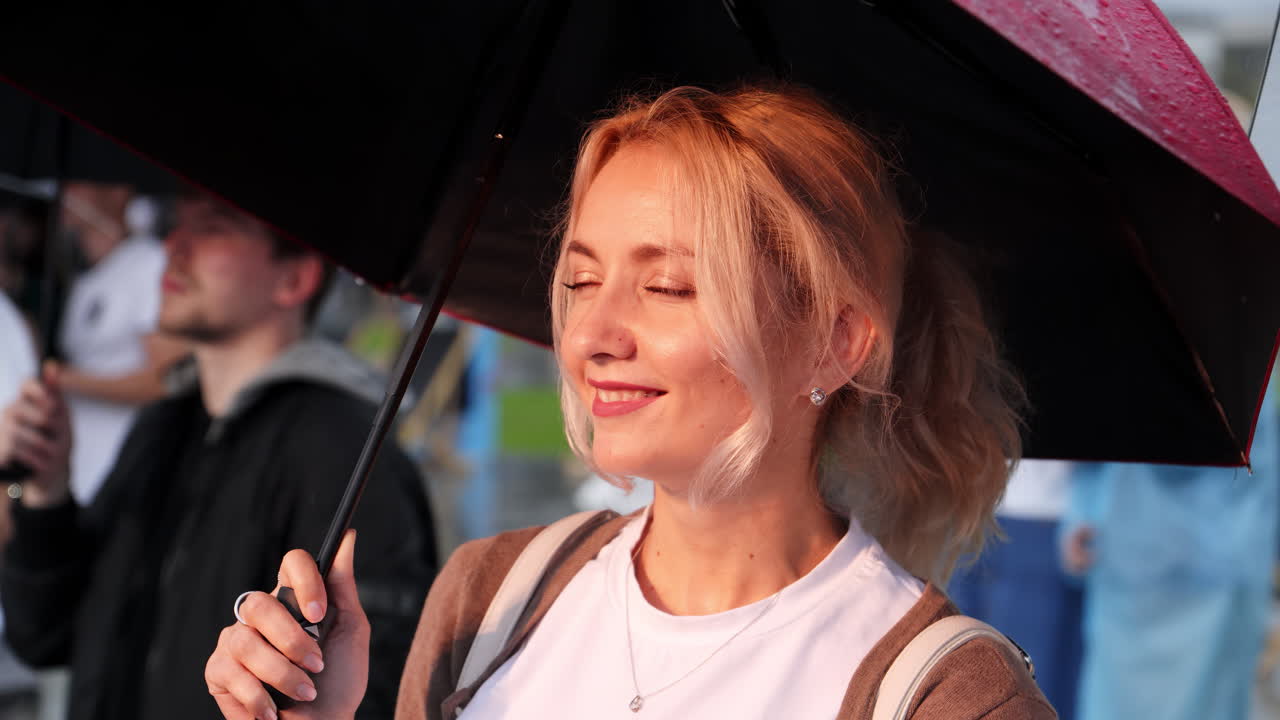 군중 가운데 우산을 들고 있는 여자