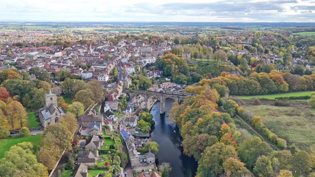 Campo lungo dall'alto che cattura la distesa della città di Knaresborough, i boschi autunnali, il fiume Nidd, l'iconico viadotto ferroviario in pietra e il paesaggio della campagna inglese nel North Yorkshire, Inghilterra